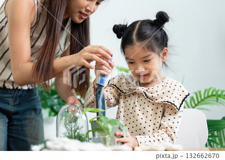 Gardening Together. A mother helps her daughter with indoor plant care. 132662670