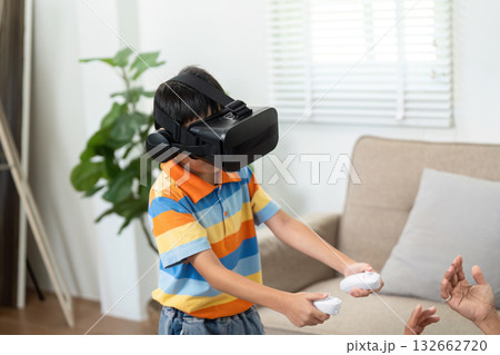 Family Fun and Virtual Reality. A child engaging in virtual reality gaming with excitement in a cozy living room. 132662720