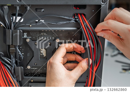 Computer Building Hands Installing Cables Inside a Modern PC Case for Optimal Performance 132662860