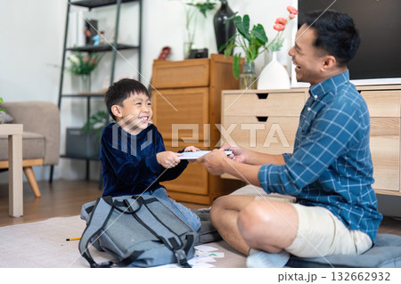 Father and son sharing a joyful moment while packing school supplies 132662932