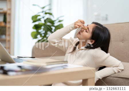 Work Stress and Relief. A woman at home rubbing her forehead in frustration while working on her laptop. 132663111