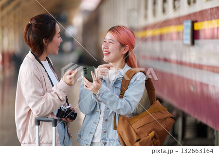 Friendship and Adventure. Two friends sharing excitement while planning their journey at the train station. 132663164