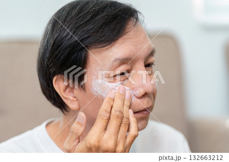 Elderly Skincare Routine. An elderly man applying moisturizer to his face, focusing on skin health. Elderly Skincare Routine. An elderly man applying moisturizer to his face, focusing on skin health. 132663212