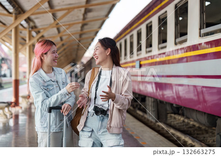 Joy and Connection. Two friends sharing a laugh and moment at the train station platform. Joy and Connection. Two friends sharing a laugh and moment at the train station platform. 132663275