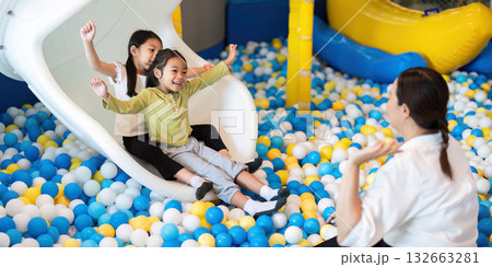 Playful Children Enjoying Slide in Colorful Ball Pit 132663281
