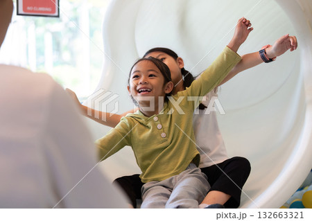 Excited Kids Sliding Down. Happy children enjoying slide at indoor playground. 132663321