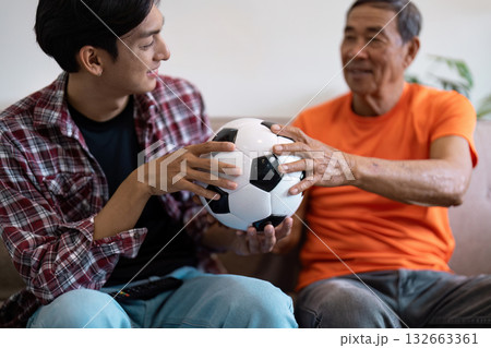 Multicultural family sharing a soccer ball at home, fostering connection and joy in a casual setting. Multicultural family sharing a soccer ball at home, fostering connection and joy in a casual setting. 132663361