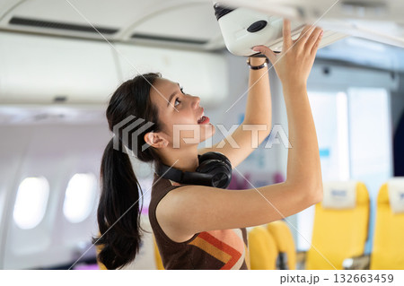 Journey and Travel. Excited traveler reaching for luggage in airplane overhead compartment. 132663459