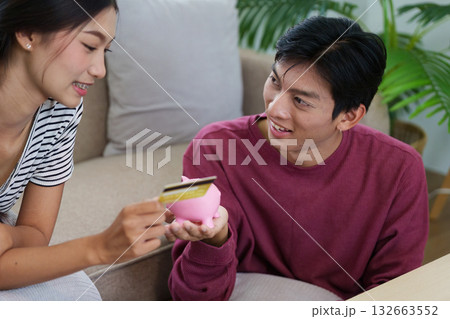 Savings and Spending. A couple learning about savings techniques while having fun with their pink piggy bank. Savings and Spending. A couple learning about savings techniques while having fun with their pink piggy bank. 132663552