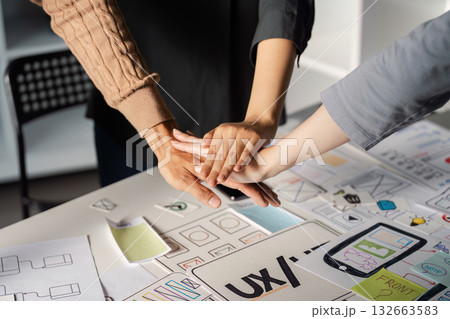 Team joining hands in solidarity during UX UI design collaboration. 132663583