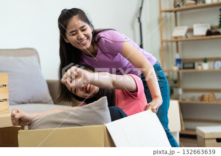 Playful fun A lesbian couple enjoying a moving box adventure Playful fun A lesbian couple enjoying a moving box adventure 132663639