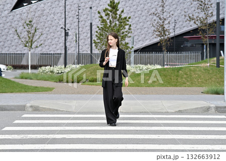 Woman crossing a street on a pedestrian crosswalk in an urban area. 132663912