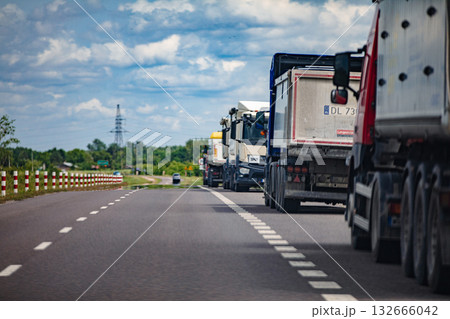 Large Heavy Trucks Drive Along a Beautiful Scenic Highway Beneath Clear Blue Skies 132666042