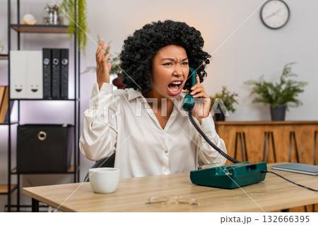 African American businesswoman yells on retro phone waving hand frustrated during angry dispute call 132666395