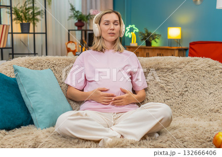 Pregnant woman meditating with headphones ocean sound stroking belly calm breathing focus deep peace Pregnant woman meditating with headphones ocean sound stroking belly calm breathing focus deep peace 132666406