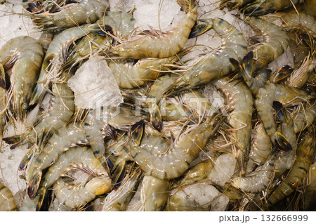 Fresh shrimps displayed on ice at a seafood market during early morning hours, showcasing their vibrant colors and textures ready for purchase or cooking 132666999