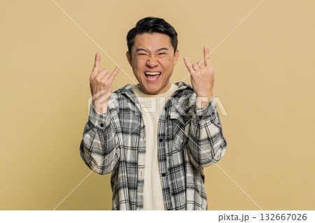 Happy Asian man showing rock n roll gesture by hands cool sign crazy expression dancing victory win Happy Asian man showing rock n roll gesture by hands cool sign crazy expression dancing victory win 132667026