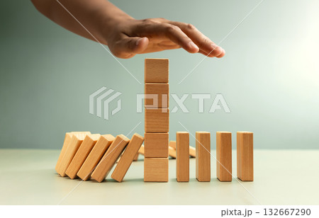 Hand stopping falling dominoes, Economic crisis prevention Hand stopping falling dominoes, Economic crisis prevention 132667290