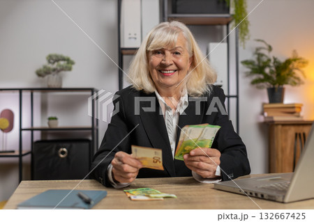 Excited senior businesswoman counting cash money dollar checking salary enjoy richness at workplace 132667425