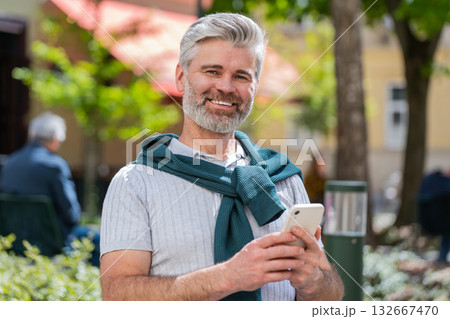 Mature man using smartphone typing text messages internet social media web app looking up thinking 132667470