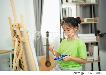 Young girl engaged in creative painting activity at home, showcasing artistic talent with watercolor palette and easel in a cozy interior setting Young girl engaged in creative painting activity at home, showcasing artistic talent with watercolor palette and easel in a cozy interior setting 132668085