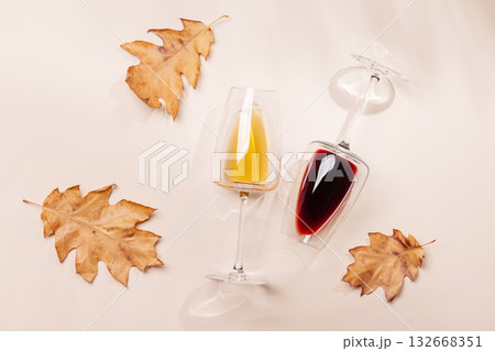 Wine glasses with autumn leaves on beige background 132668351