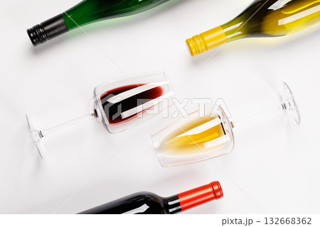 Wine glasses with red and white wine and bottles lying on white background 132668362
