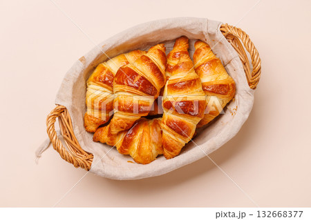Freshly baked croissants in wicker basket on light background 132668377