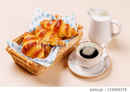 Aromatic croissants in wicker basket with cup of coffee 132668378