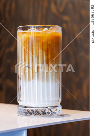Iced latte in a clear glass with visible coffee and milk layers 132668392