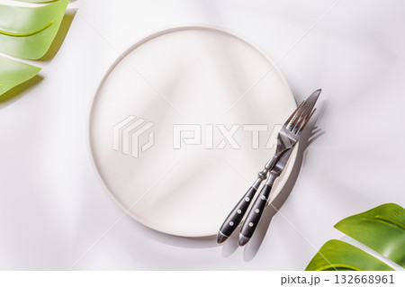 Empty plate on white background with leaves and shadows, food mockup with natural light Empty plate on white background with leaves and shadows, food mockup with natural light 132668961