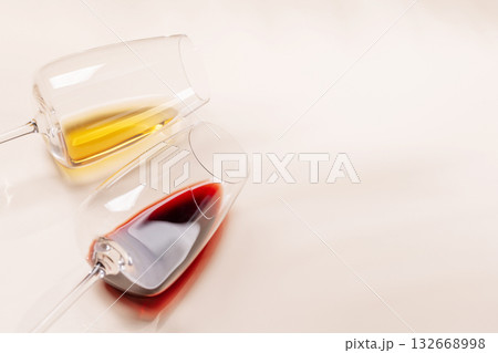 Wine glasses with red and white wine lying on beige background Wine glasses with red and white wine lying on beige background 132668998