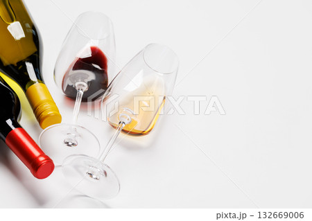 Wine glasses with red and white wine and bottles lying on white background Wine glasses with red and white wine and bottles lying on white background 132669006