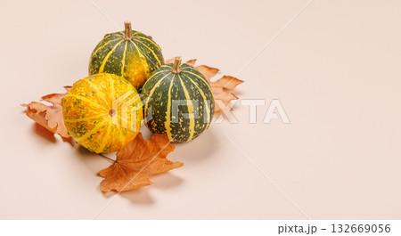 Autumn still life with pumpkins and leaves on beige background 132669056