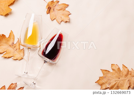 Wine glasses with autumn leaves on beige background 132669073