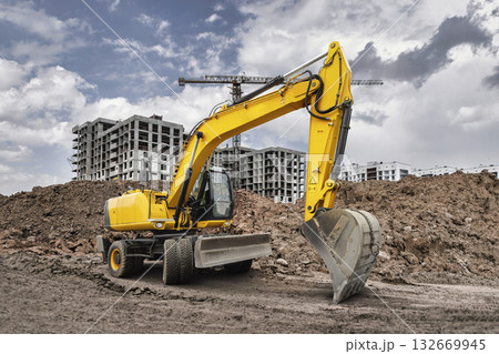 Heavy excavator works diligently at a construction site, moving dirt and preparing the ground for new buildings amidst a cloudy sky. Heavy excavator works diligently at a construction site, moving dirt and preparing the ground for new buildings amidst a cloudy sky. 132669945