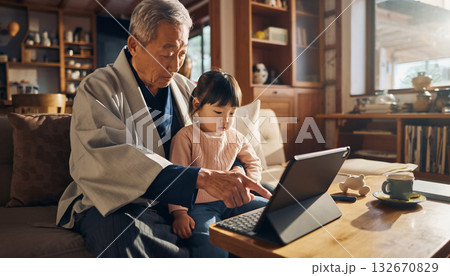 高齢男性が孫と一緒にタブレットを操作する家族の時間 132670829