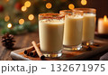 Three glasses of eggnog with cinnamon on a wooden board, surrounded by spices and blurred holiday lights in the background. Cozy holiday concept 132671975