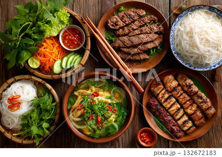Vietnamese food feast featuring grilled meats, noodles, and fresh herbs 132672183