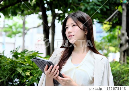 公園の緑の中でタブレットを使う若いビジネスウーマン 公園の緑の中でタブレットを使う若いビジネスウーマン 132673148