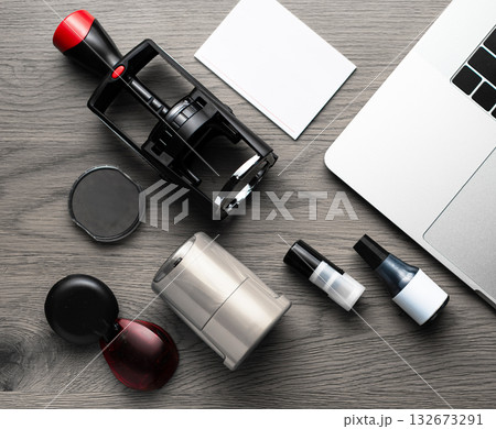 Set of stamps, ink bottles, and laptop on wooden desk Set of stamps, ink bottles, and laptop on wooden desk 132673291
