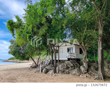 Secluded White Beach Hut or Wooden Cabin on Sand and Rocks, Surrounded by Lush Green Trees on a Tropical Island Secluded White Beach Hut or Wooden Cabin on Sand and Rocks, Surrounded by Lush Green Trees on a Tropical Island 132673672