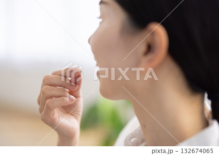 口元に錠剤を運ぶ女性の手元のクローズアップ 口元に錠剤を運ぶ女性の手元のクローズアップ 132674065