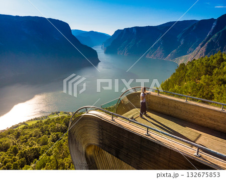 Tourist enjoying fjord view on Stegastein viewpoint Norway Tourist enjoying fjord view on Stegastein viewpoint Norway 132675853