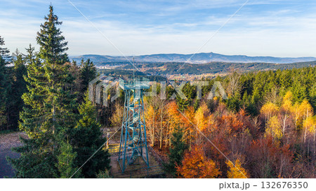Slovanka Lookout Tower rises above the vibrant autumn foliage of Jizera Mountains. This historic iron tower offers stunning views of the surrounding landscape, showcasing fall colors. 132676350