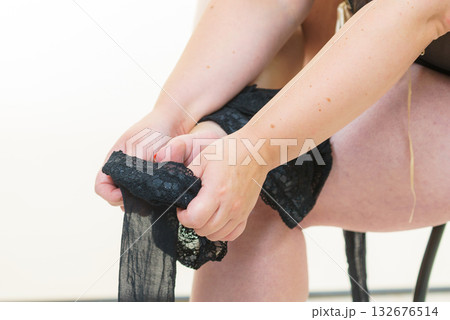 Woman plus size puts on black nylon stockings 132676514