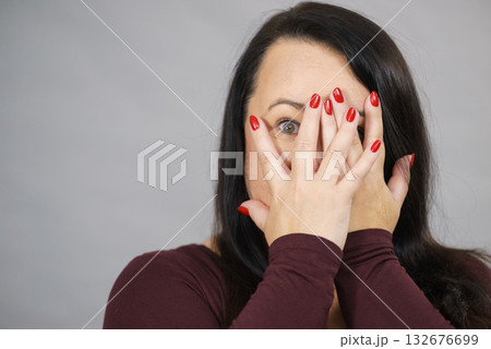 Woman peeking through her hands 132676699