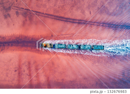 Aerial view of an old train rides on the railway laid in the water through the salt lake. Salt mining in Lake Burlin. Altai. Bursol. 132676983