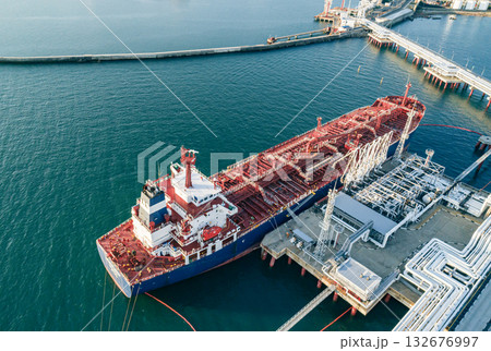 Aerial view of a large oil tanker docked at a pier in the port in process of loading. 132676997