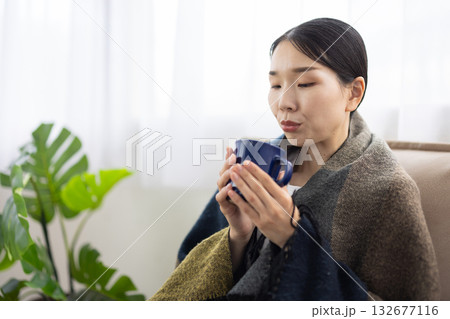 マグカップのホットドリンクに息をふきかける女性 132677116
